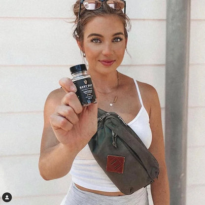 A fit and attractive woman confidently holding a bottle of 25mg CBD Softgels, emphasizing their role in promoting a healthy lifestyle and restorative sleep.
